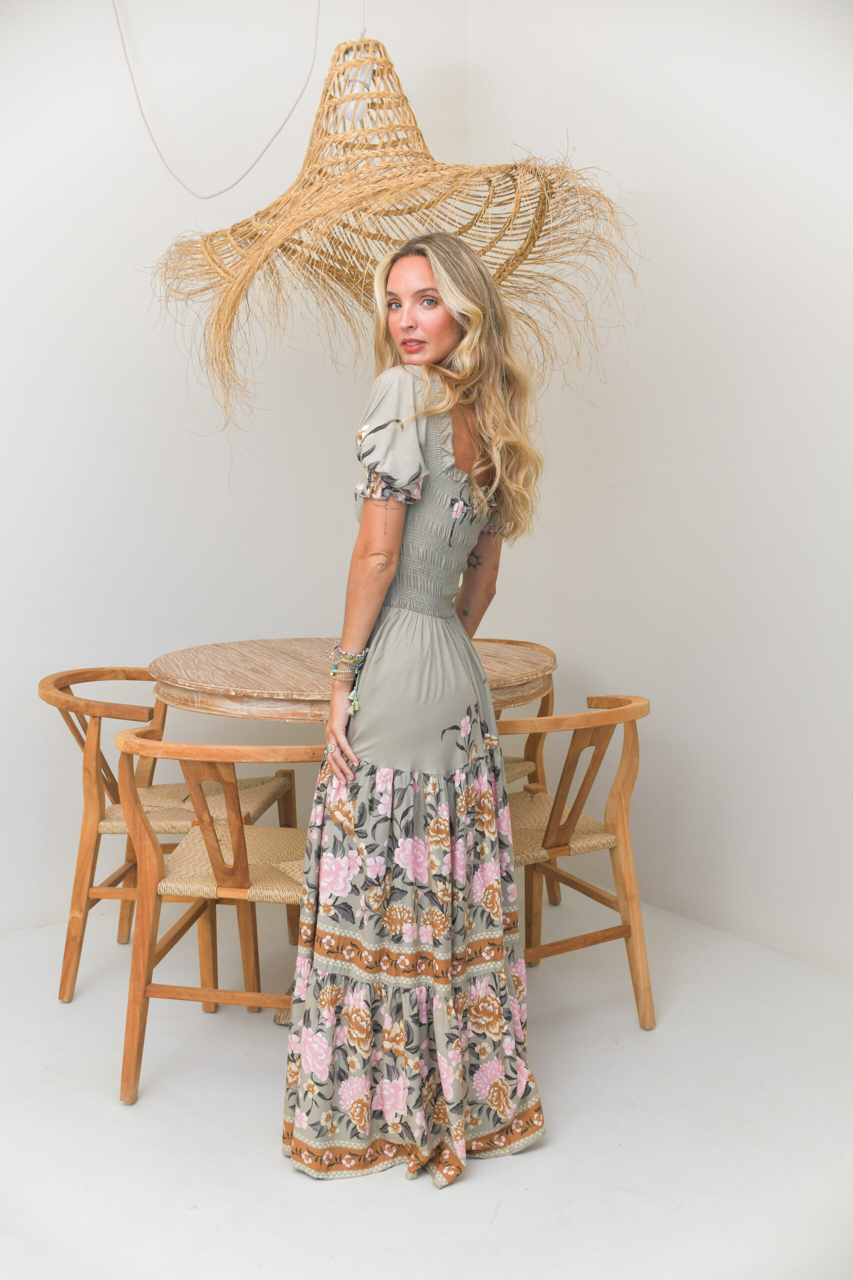 Vestido maxi boho estampado floral en rosas blancos y tostados sobre fondo verde claro, escote palabra de honor elástico corpiño fruncido y mangas cortas con puños elásticos y dobladillo con volantes en capas Neandnu