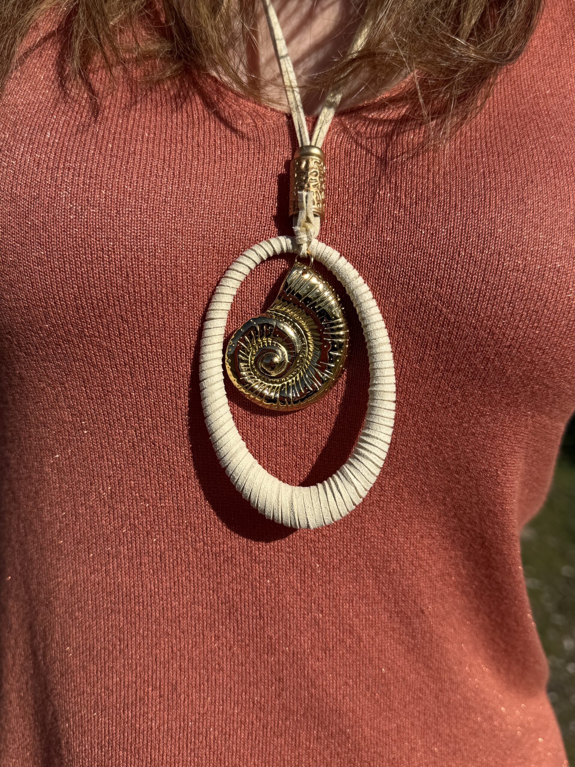 collar largo hecho a mano de cordón regulable de antelina color crudo rematado con aro ovalado con detalle de caracola de laton dorado en su interior Neandnu