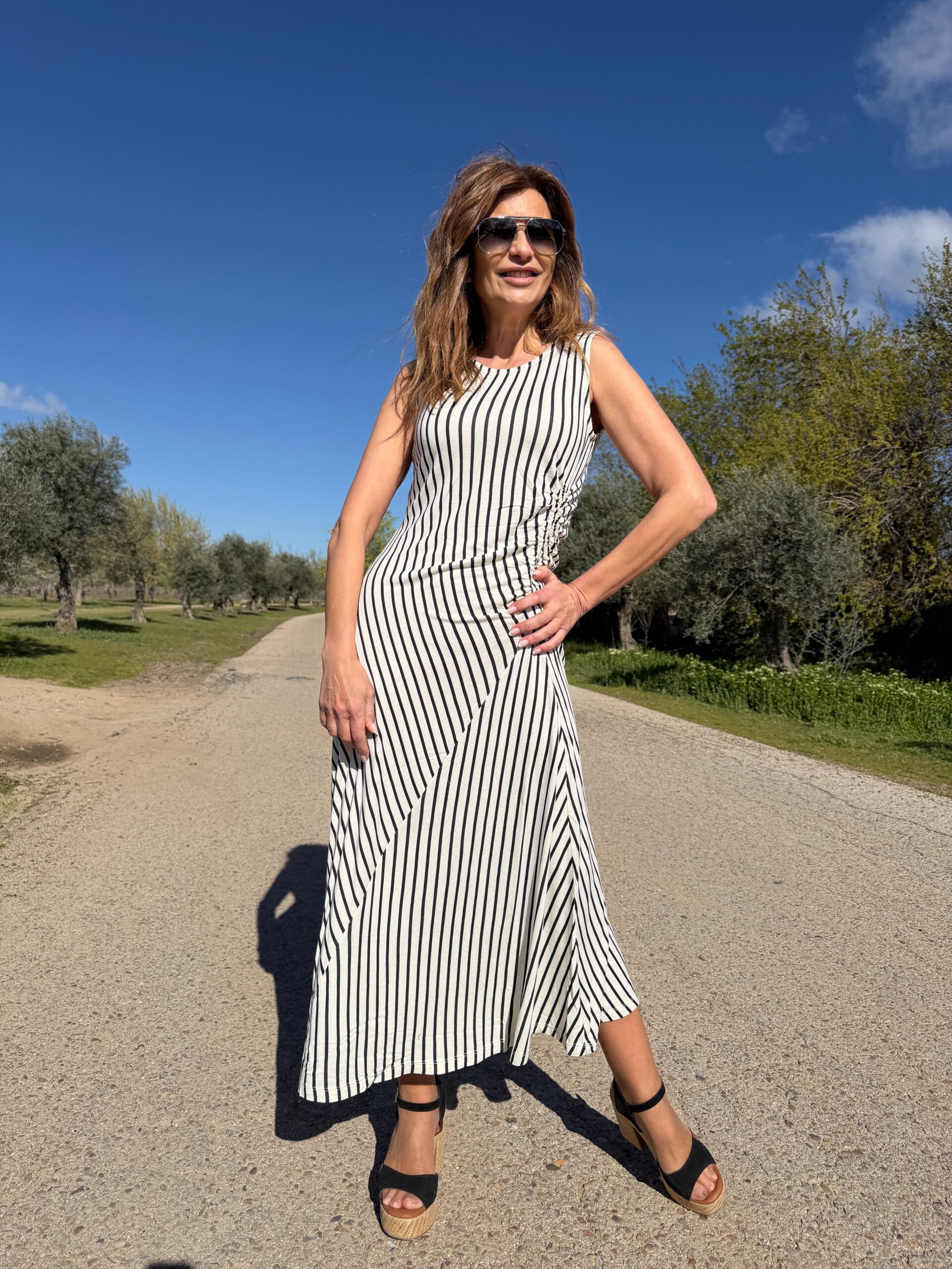 Vestido midi sin mangas estampado de rayas de color negro sobre fondo blanco cuello redondo cintura con detalle elástico y cierre posterior con botón y abertura lagrima Neandnu