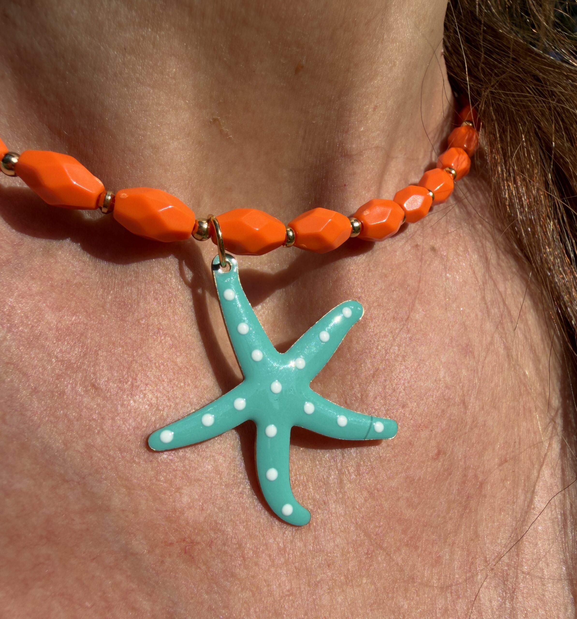 collar largo de cuentas de resina naranjas y motivos dorados acabado en estrella de mar esmaltada color azul con puntitos blancos Neandnu